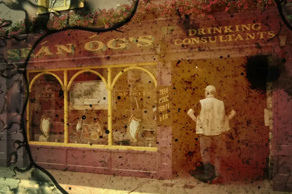 Pub-Fassade mit der Aufschrift Seán Og's, davor ein Mann von hinten, das Bild ist von Flecken und dunklen Linien überzogen